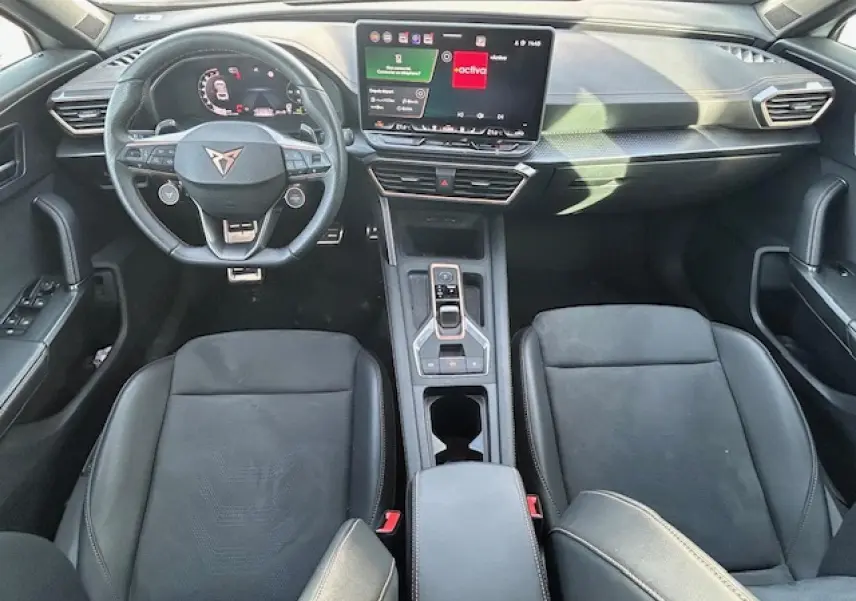 Vue intérieure avant du CUPRA Formentor 2025, tableau de bord moderne avec écran tactile et volant cuir noir.