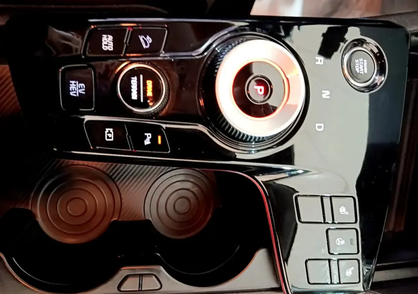 Gros plan sur la console centrale noire brillante du Kia Sportage 2022 avec sélecteur rotatif et boutons de commande.