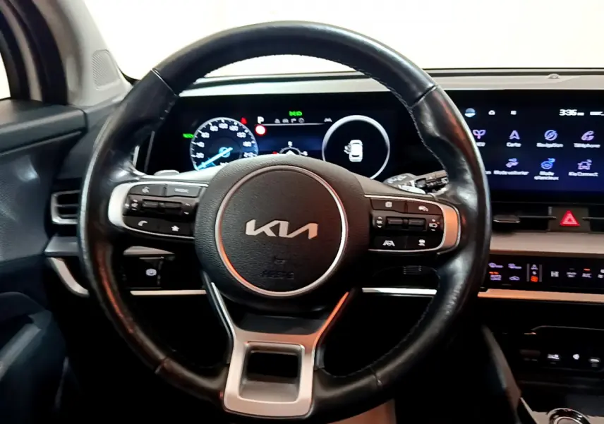Vue intérieure centrée sur le volant cuir KIA avec tableau de bord numérique et écran tactile du Sportage blanc 2022.