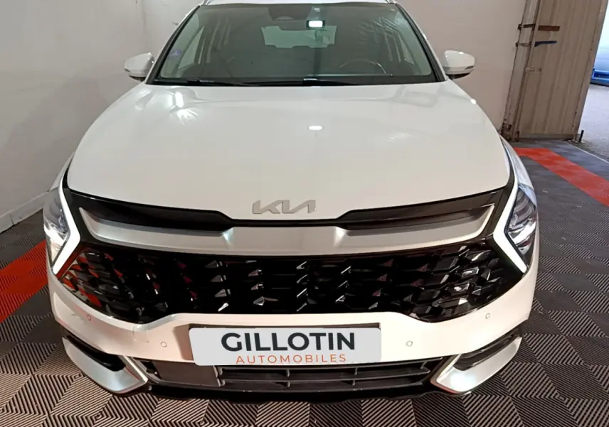 Vue avant rapprochée d'un KIA Sportage blanc 2022 avec calandre noire brillante et phares LED en V.