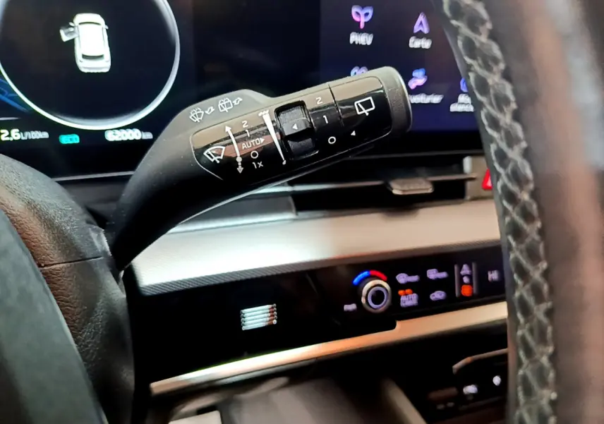 Gros plan sur la commande d’essuie-glace à gauche du volant dans l’habitacle du KIA SPORTAGE blanc 2022 hybride rechargeable.