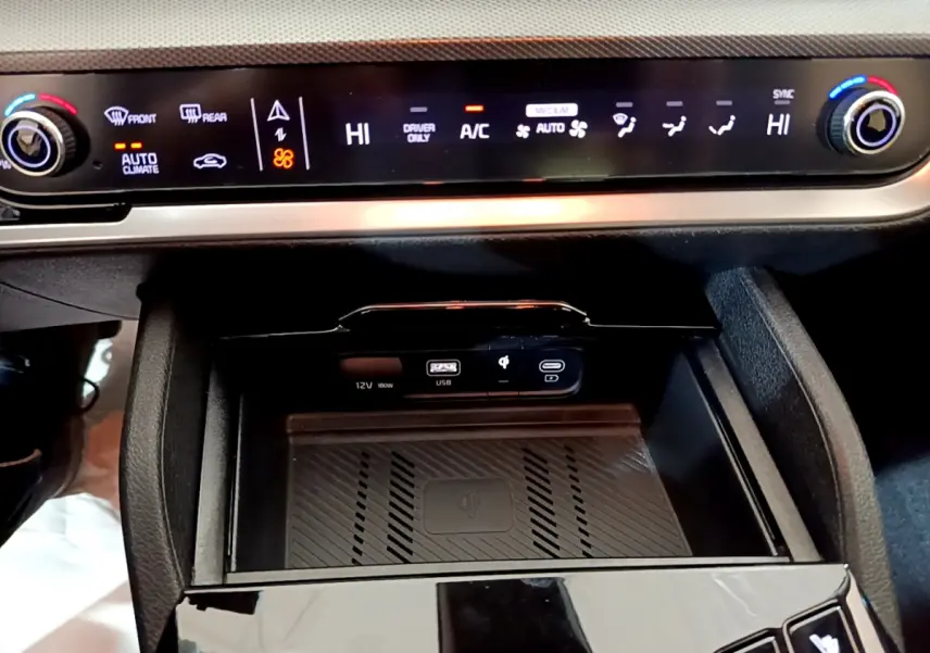 Détail de la console centrale du Kia Sportage blanc 2022 avec commandes climatisation et zone de recharge sans fil.