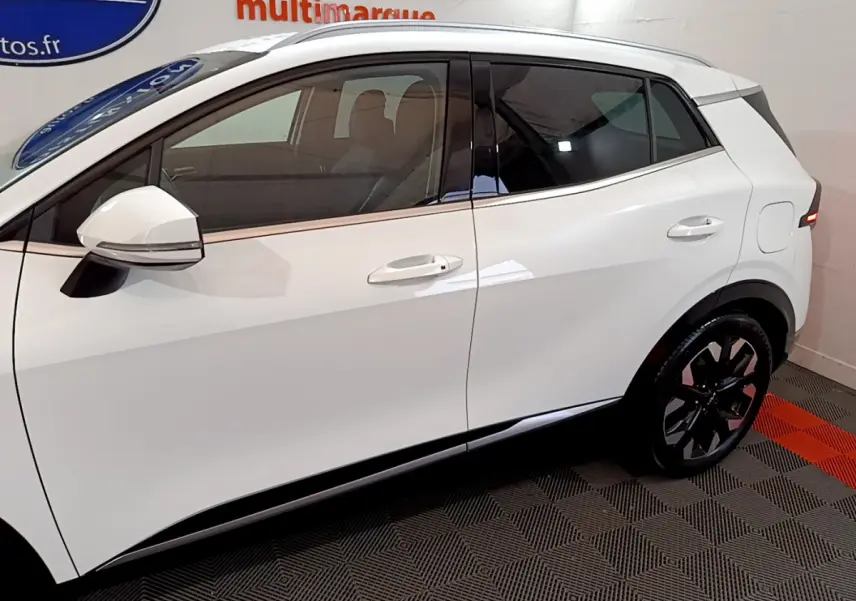 Vue latérale droite du KIA SPORTAGE blanc 2022 avec jantes noires et rétroviseurs blancs intégrant clignotants.