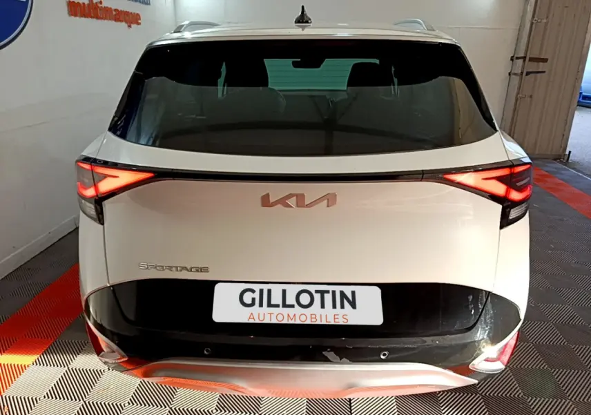 Vue arrière d'un KIA Sportage blanc 2022 avec feux LED allumés et logo KIA visible sur le hayon.