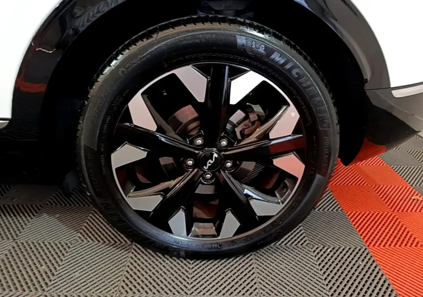 Gros plan sur la roue avant droite du Kia Sportage blanc 2022 avec jante noire et argentée au design moderne.