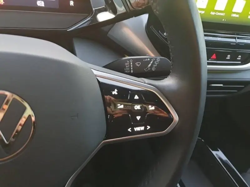 Gros plan sur le volant noir cuir du Volkswagen ID.4 2023, avec commandes tactiles et tableau de bord partiel visible.