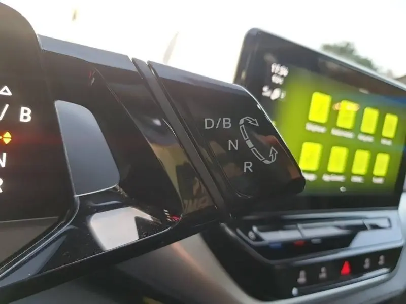Gros plan sur la commande de boîte automatique du Volkswagen ID.4 2023, avec écran tactile et tableau de bord visibles.