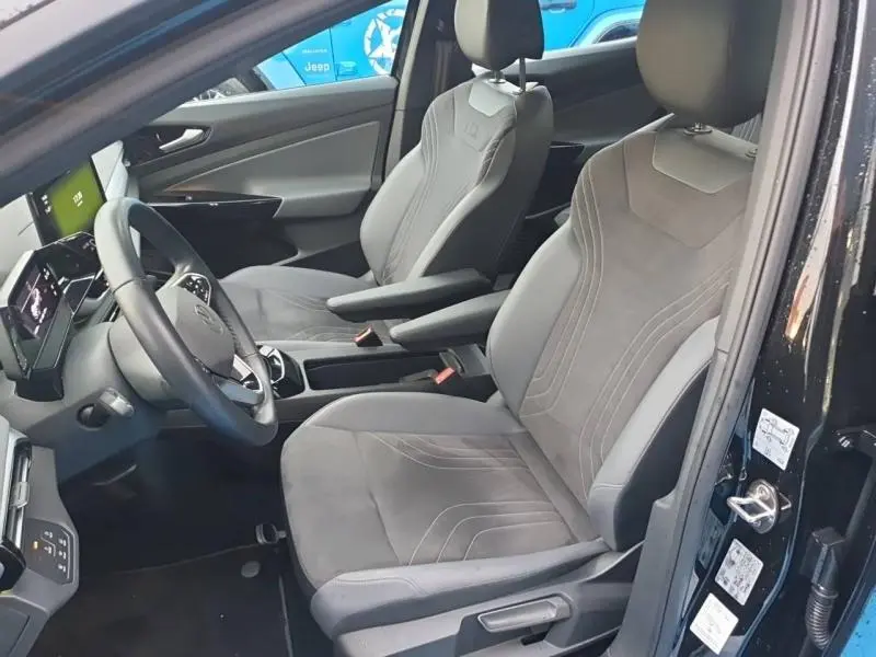 Intérieur avant du Volkswagen ID.4 148ch noir, vue côté conducteur montrant sièges en tissu gris avec logo ID.