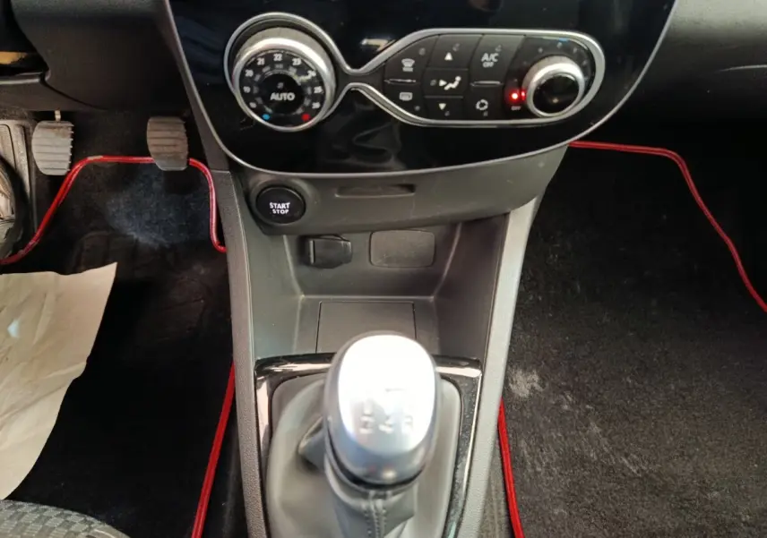 Vue rapprochée de la console centrale de la Renault Clio Intens rouge 2018 avec levier de vitesse manuel et bouton start/stop.