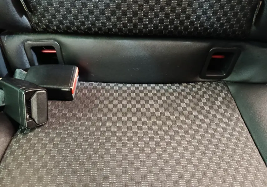 Gros plan sur la banquette arrière noire à motifs carrés avec boucle de ceinture de sécurité visible.