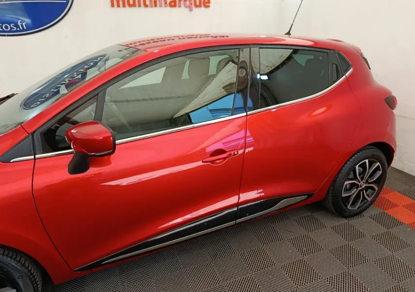 Profil côté gauche de la Renault Clio Intens rouge 2018, mettant en valeur les jantes et les détails chromés sur la porte.