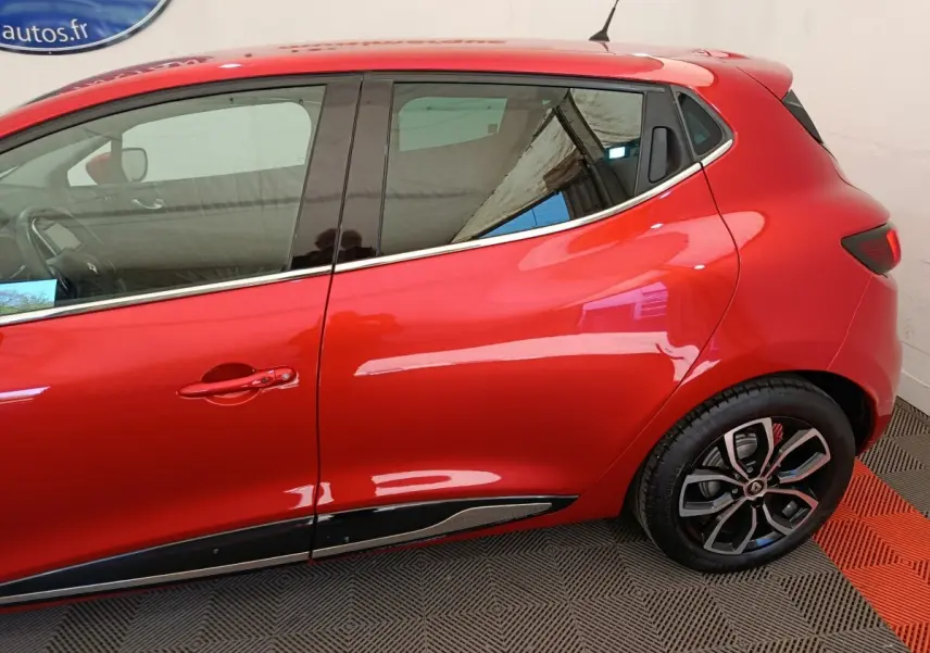 Vue latérale droite d'une Renault Clio Intens rouge de 2018, mettant en valeur la ligne fluide et les jantes alliage noires.