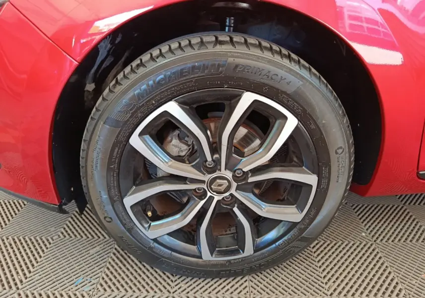 Gros plan sur la roue avant gauche d'une Renault Clio rouge, jante alliage au design moderne et pneu Michelin.