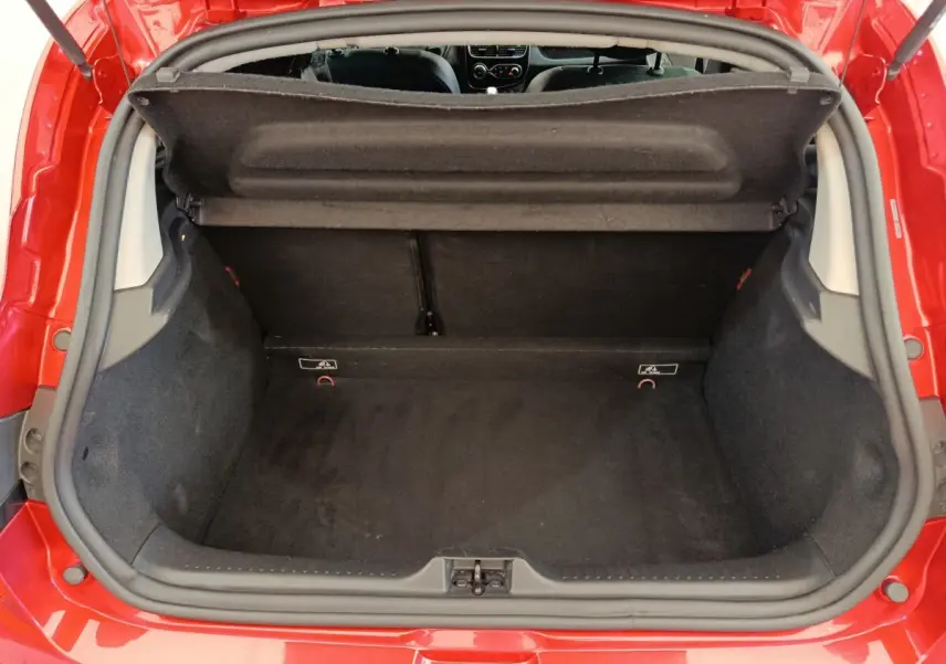 Coffre ouvert vu de l'arrière d'une Renault Clio Intens Energy TCe 90 rouge, intérieur noir et tablette de coffre relevée.