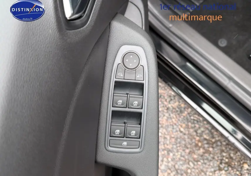 Gros plan sur les commandes des vitres électriques et rétroviseurs côté gauche de la porte d’une Renault Clio V noire.