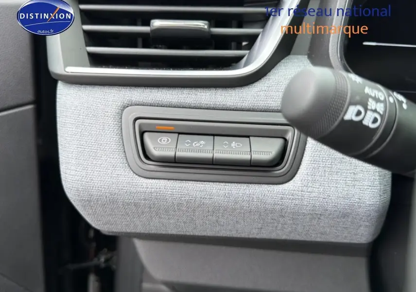Détail des commandes d'éclairage et verrouillage sur tableau de bord tissu gris clair d'une Renault Clio V noire.