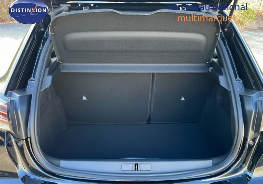 Coffre ouvert vu de l'arrière d'une Peugeot 208 Hybrid 110ch noir perla metal, espace de chargement vide et propre.