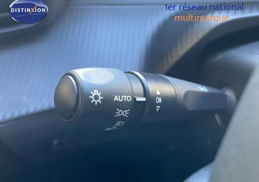 Gros plan sur la commande des phares du Peugeot 208 Hybrid 110ch, intérieur noir, détails des symboles lumineux.