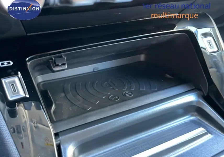 Détail de la console centrale noire perla metal de la Peugeot 208 Hybrid 110ch, avec zone de rangement et chargeur sans fil.
