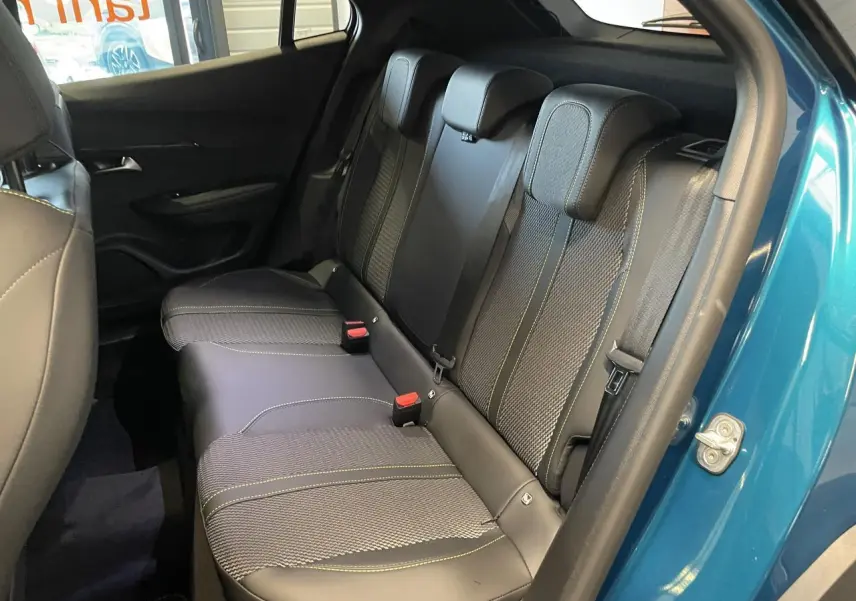 Banquette arrière en tissu et cuir noir avec surpiqûres vertes, vue côté droit porte ouverte d’un Peugeot 2008 bleu.
