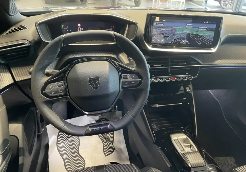 Vue intérieure centrée sur le volant compact Peugeot 2008 GT avec écran tactile 10'' et finitions carbone et surpiqûres vertes