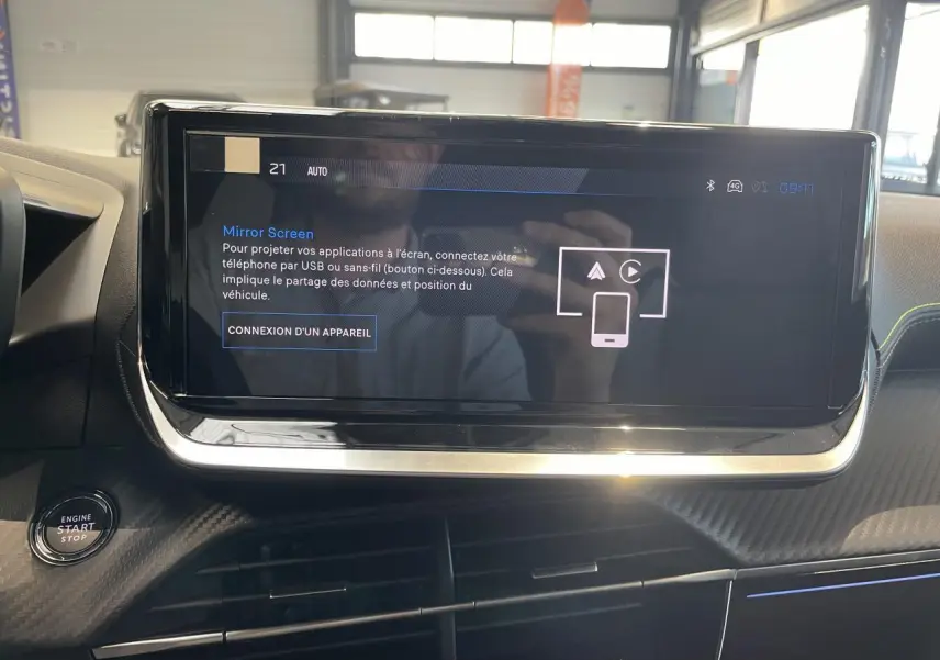 Écran tactile central en gros plan dans l’habitacle noir du Peugeot 2008 bleu, avec bouton démarrage visible à gauche.