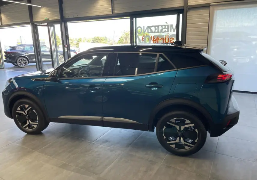 Peugeot 2008 hybride bleu vue de profil côté gauche, toit noir et jantes bicolores en concession.