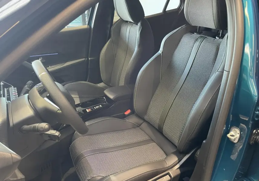 Vue intérieure côté conducteur du Peugeot 2008 bleu, mettant en valeur les sièges sport noirs avec surpiqûres contrastées.