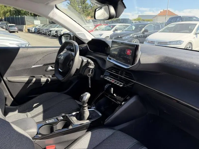 Intérieur de Peugeot 208 1.2 100ch Allure vue côté conducteur, volant, écran tactile et boîte manuelle visibles.