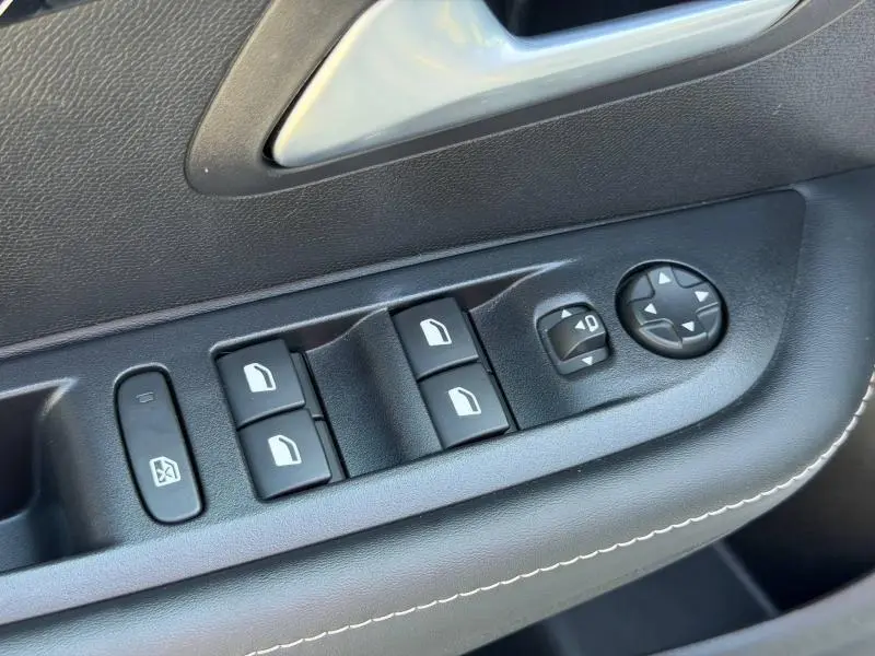 Détail des commandes de lève-vitres et réglage des rétroviseurs sur la porte côté conducteur d'une Peugeot 208 blanche.