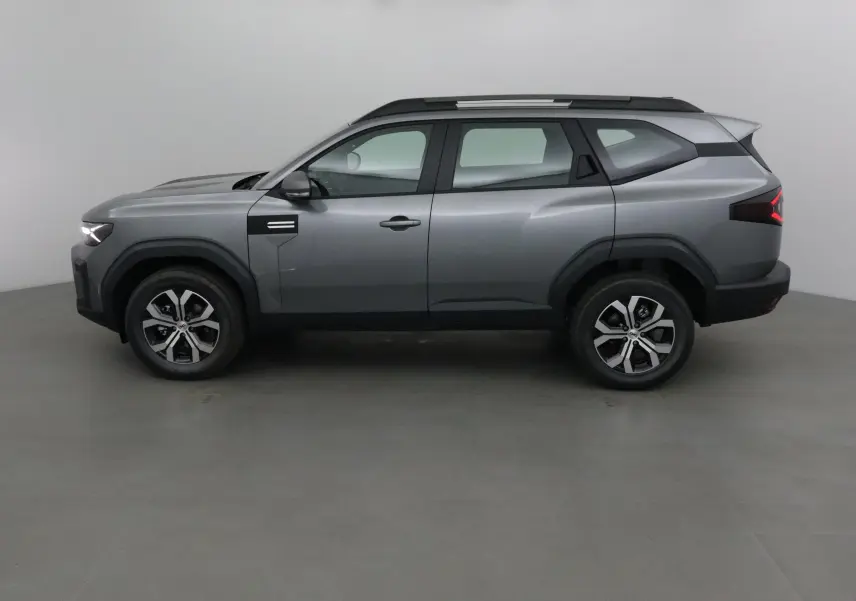 Profil côté gauche du SUV Dacia Bigster gris schiste 2025 avec jantes alliage et toit noir contrasté.