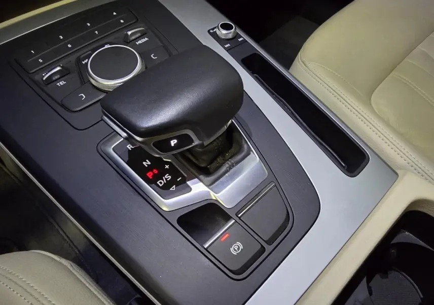 Gros plan sur la console centrale beige de l'Audi Q5 2019 avec levier de vitesse automatique et commandes multimédia.