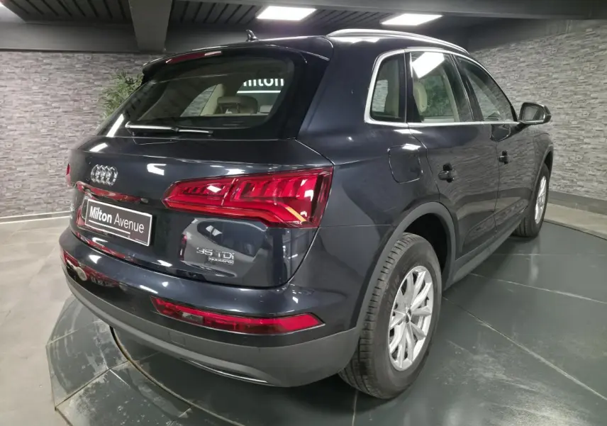 Audi Q5 bleu métallisé vu en 3/4 arrière droit, avec feux arrière LED et jantes aluminium 17 pouces.