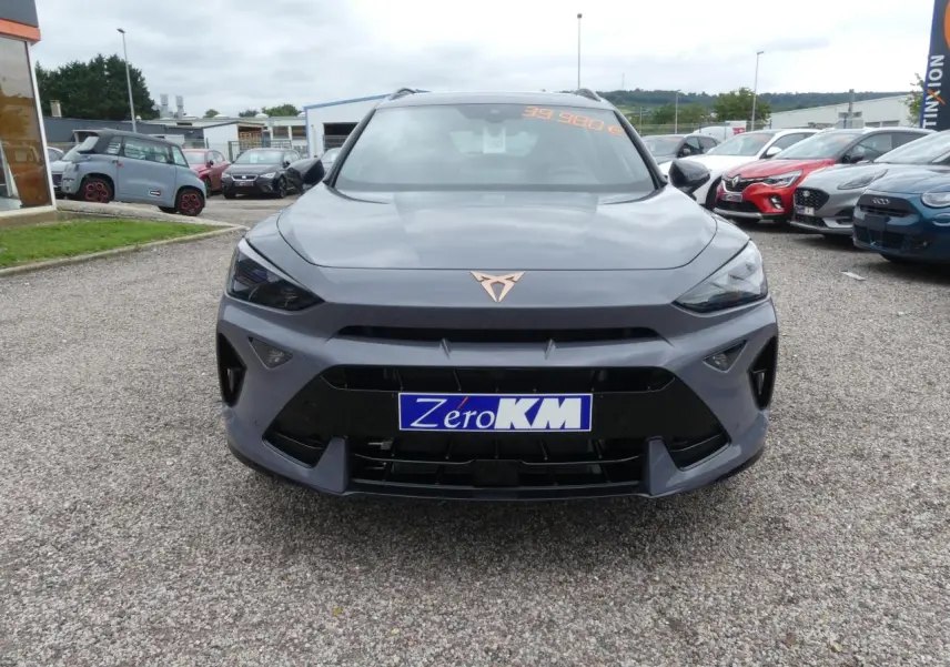 Vue frontale d'une CUPRA Formentor gris Graphène avec logo cuivré et calandre noire sportive sur parking.