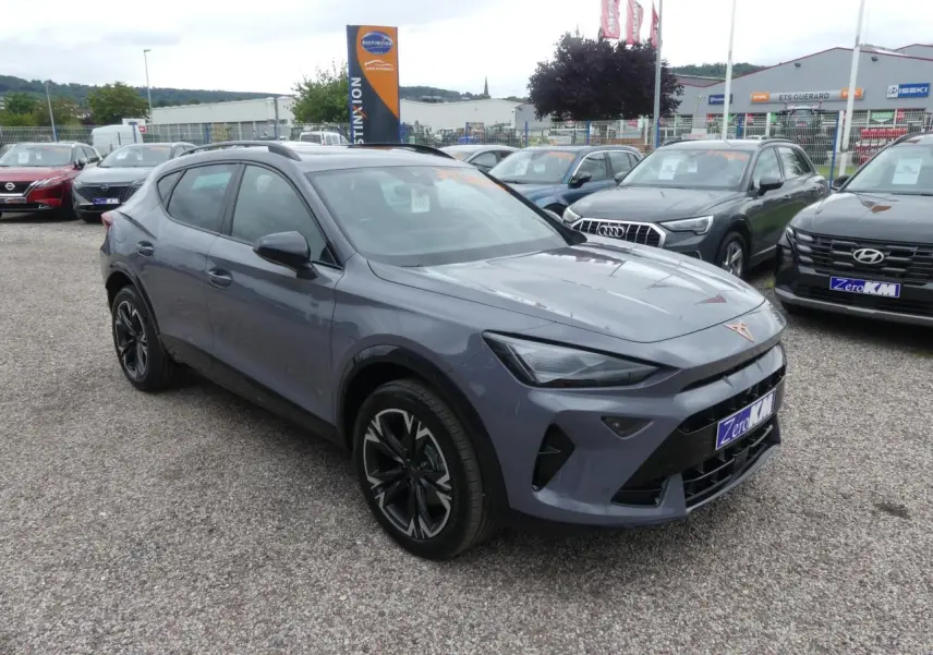 CUPRA Formentor gris Graphène en 3/4 avant avec coques de rétroviseurs noires sur parking extérieur.