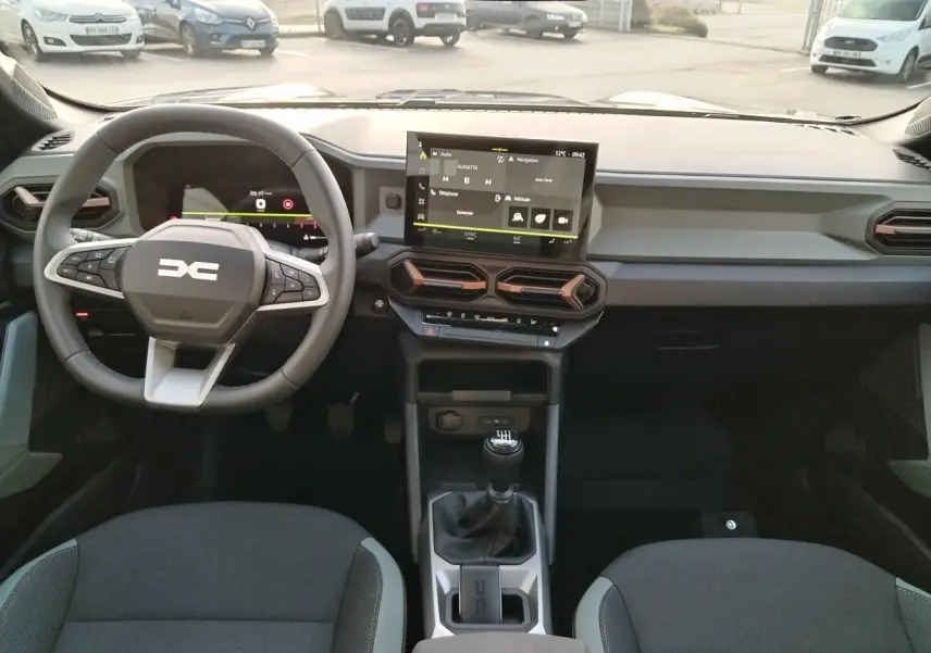 Intérieur du Dacia Bigster 2025 en vue frontale, tableau de bord moderne avec écran tactile et levier de vitesses manuel.