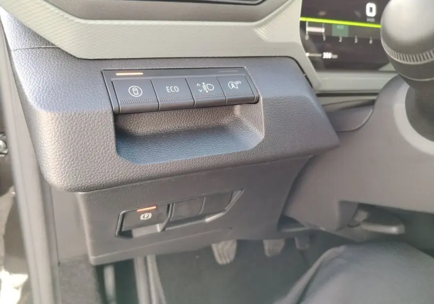 Gros plan sur les commandes à gauche du volant dans l'habitacle noir du Dacia Bigster 2025, avec bouton ECO et frein à main électronique.