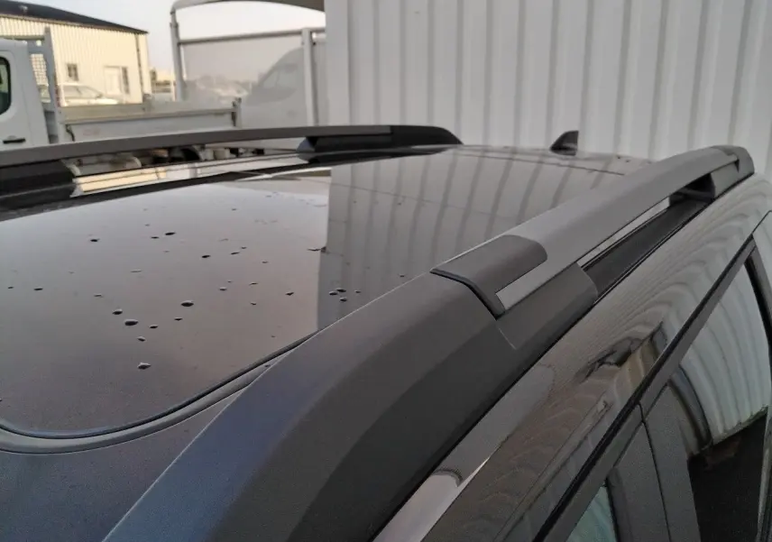 Gros plan sur le toit noir du Dacia Bigster 2025 avec barres de toit et gouttes de pluie visibles.
