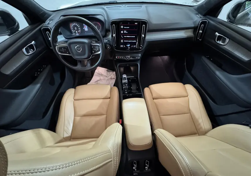 Vue intérieure avant du Volvo XC40 Recharge T5 avec sièges cuir beige et tableau de bord noir moderne à écran tactile central.