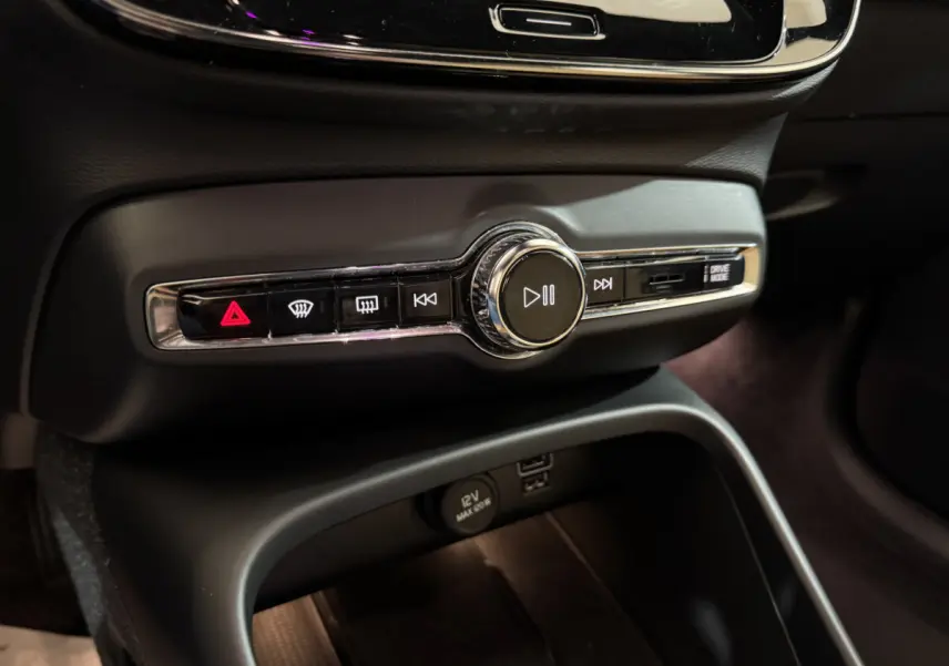 Gros plan sur la console centrale noire du Volvo XC40 Recharge T5 avec commandes multimédia et bouton hazard rouge.