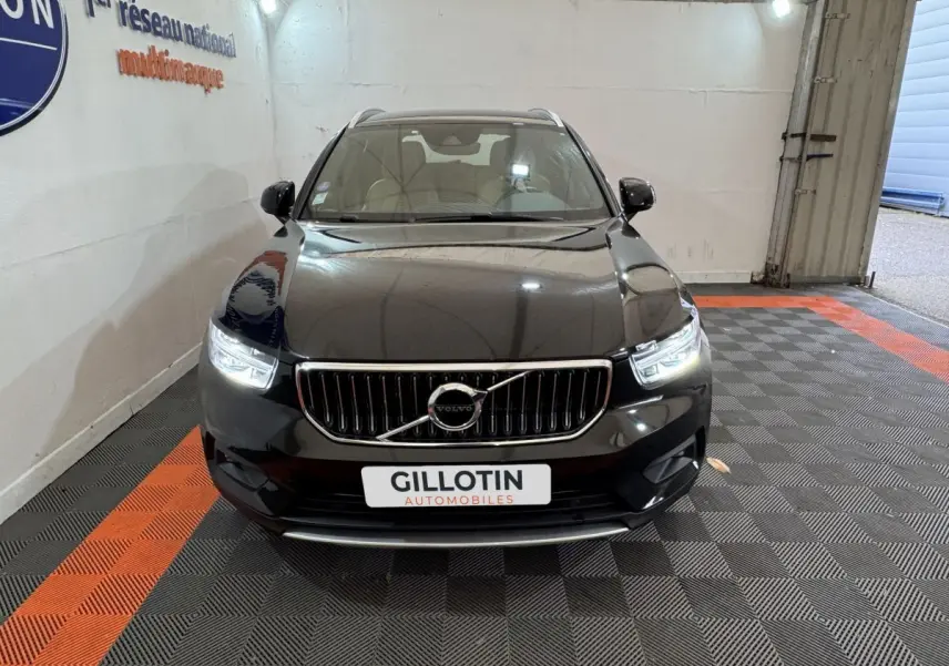 Vue frontale d'un Volvo XC40 Recharge T5 noir avec phares LED allumés dans un showroom.