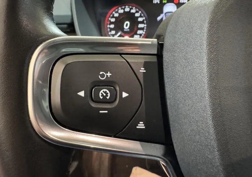 Gros plan sur les commandes de régulateur de vitesse au volant cuir du Volvo XC40 Recharge T5 noir de 2021.