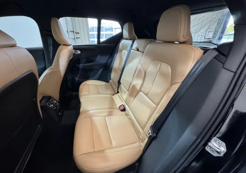 Vue intérieure côté droit sur la banquette arrière cuir beige du Volvo XC40 noir, avec ceinture de sécurité et porte ouverte.
