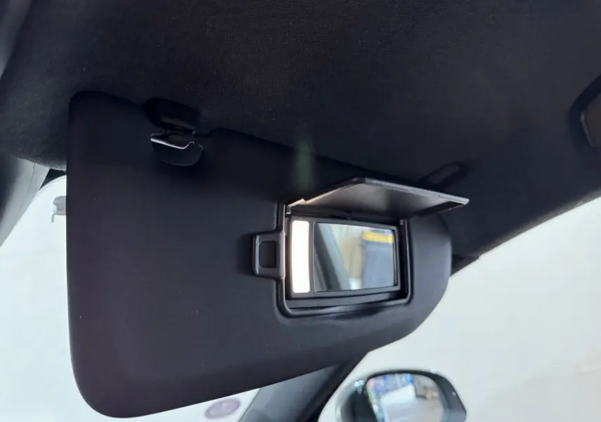 Miroir de courtoisie ouvert sur le pare-soleil côté conducteur dans l'habitacle noir du Volvo XC40 Recharge T5.