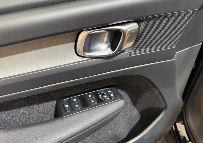 Gros plan sur la poignée intérieure et les commandes de vitres côté conducteur du Volvo XC40 noir, finition Inscription.