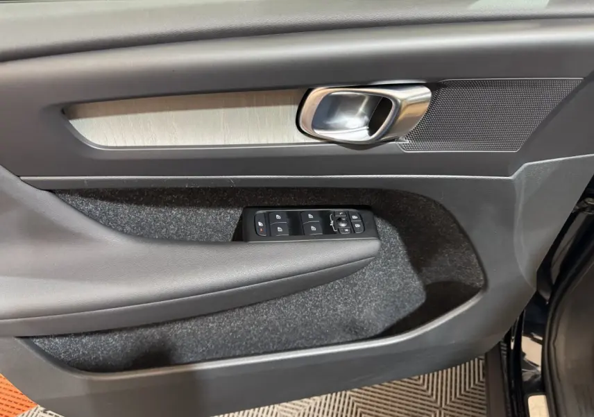 Gros plan sur la porte avant gauche noire du Volvo XC40 Recharge T5 avec commandes de vitres et poignée métal.