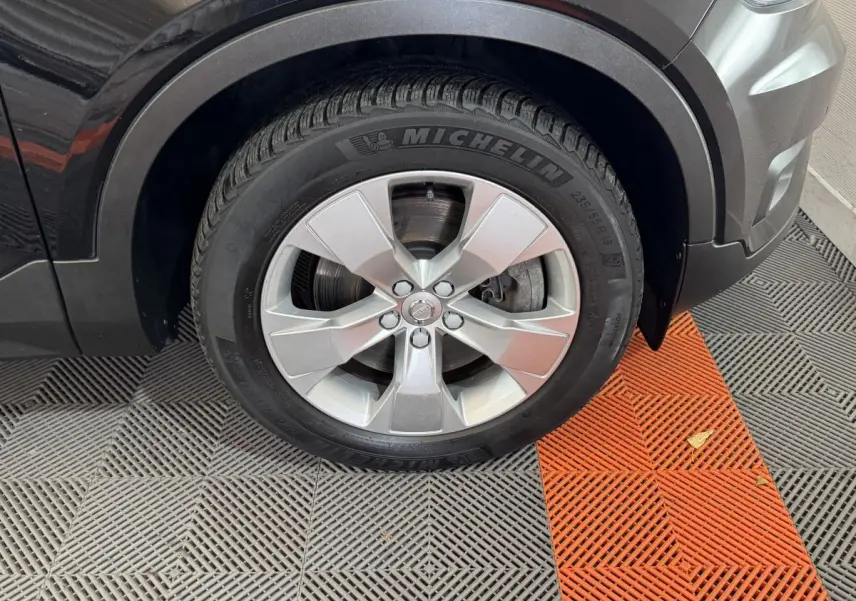 Gros plan sur la roue avant droite noire d'un Volvo XC40 Recharge T5 262 DCT7 Inscription avec jante argentée Michelin.