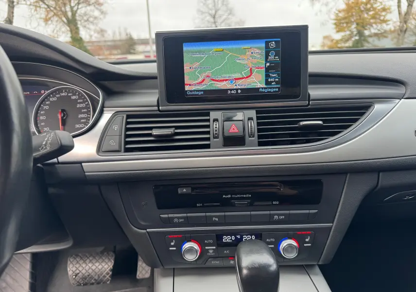 Vue intérieure du tableau de bord de l'Audi A6 Avant 2015, avec écran GPS central et commandes de climatisation.