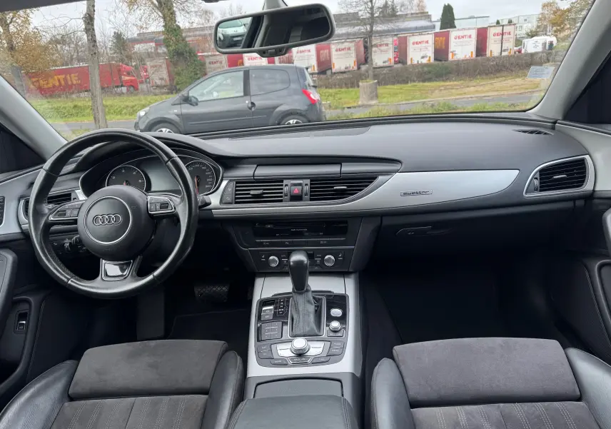 Vue intérieure de l'Audi A6 Avant 2015, tableau de bord et console centrale avec volant cuir et finition aluminium Quattro.