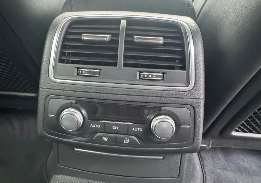 Détail de la console arrière noire de l’Audi A6 Avant 2015 avec commandes de climatisation et aérateurs.